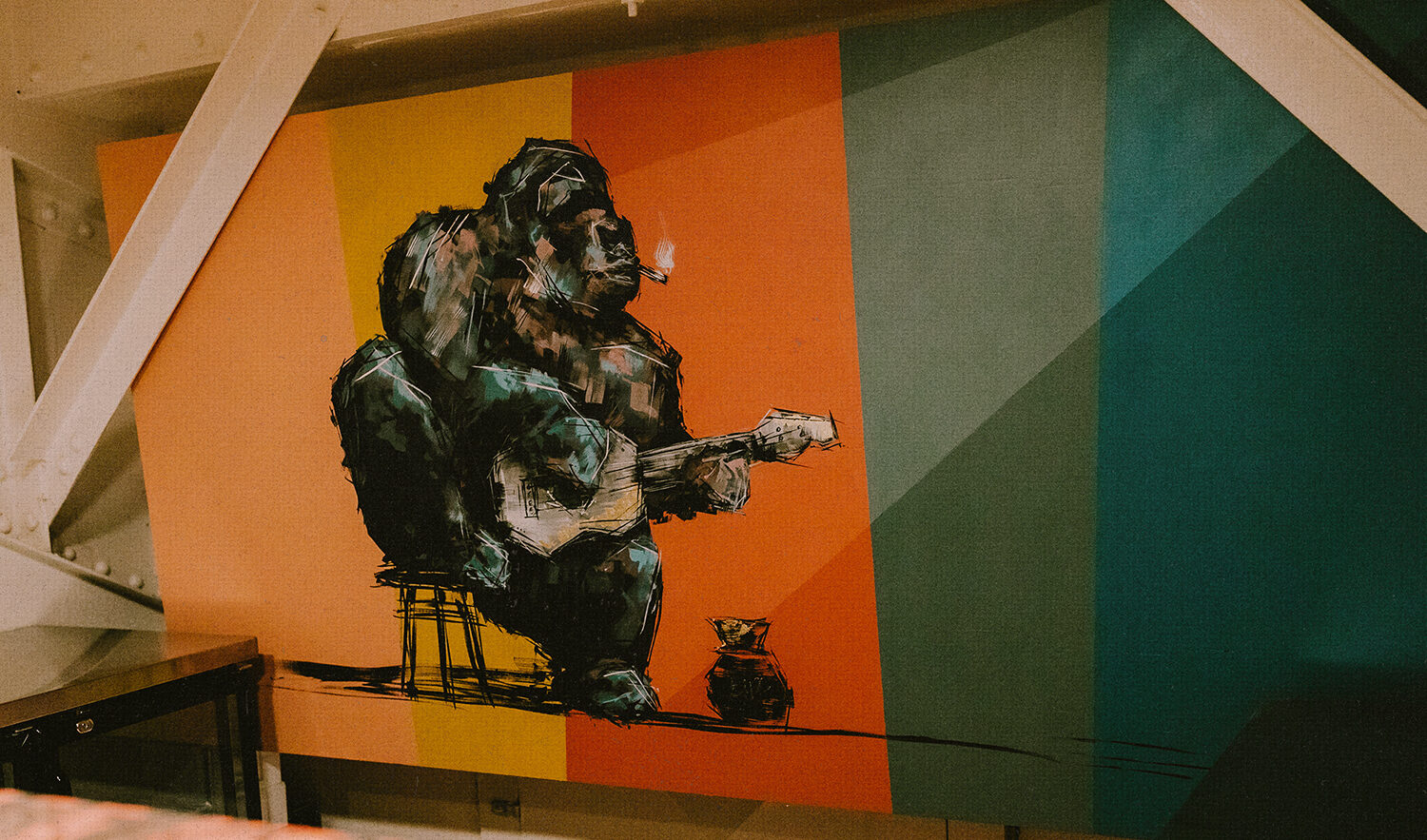 A painting depicts a gorilla playing a guitar and smoking.