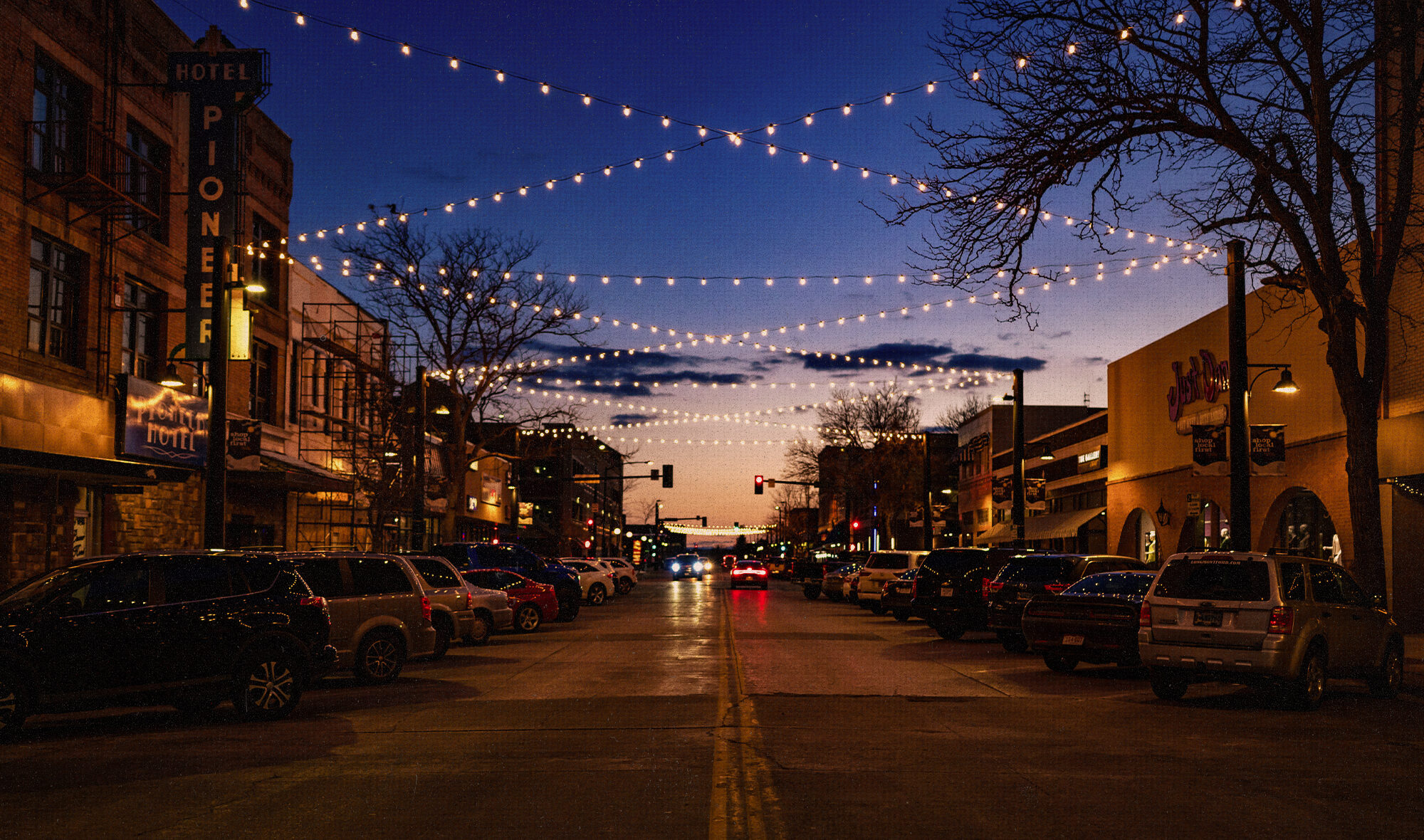String lights criss-cross overhead down a street at night time.