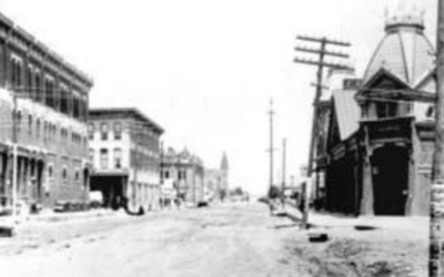 CAPITOL-NORTH-1885 A photo from 1885, showing a dirt road with buildings.