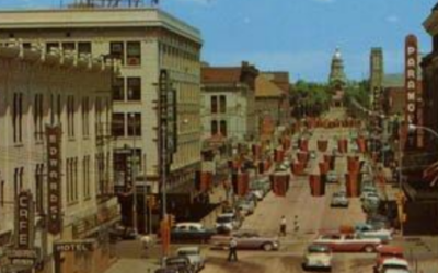 CAPITOL-NORTH-1957 A colorized photo of downtown Cheyenne, showing streets lined with cars.
