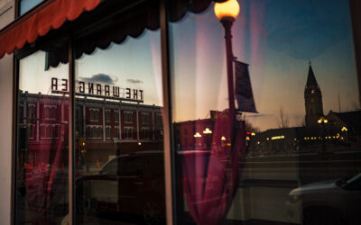 Window Reflection – 1 A reflection of Downtown Cheyenne, showcasing the Depot Clock Tower and exterior signage for The Wrangler.