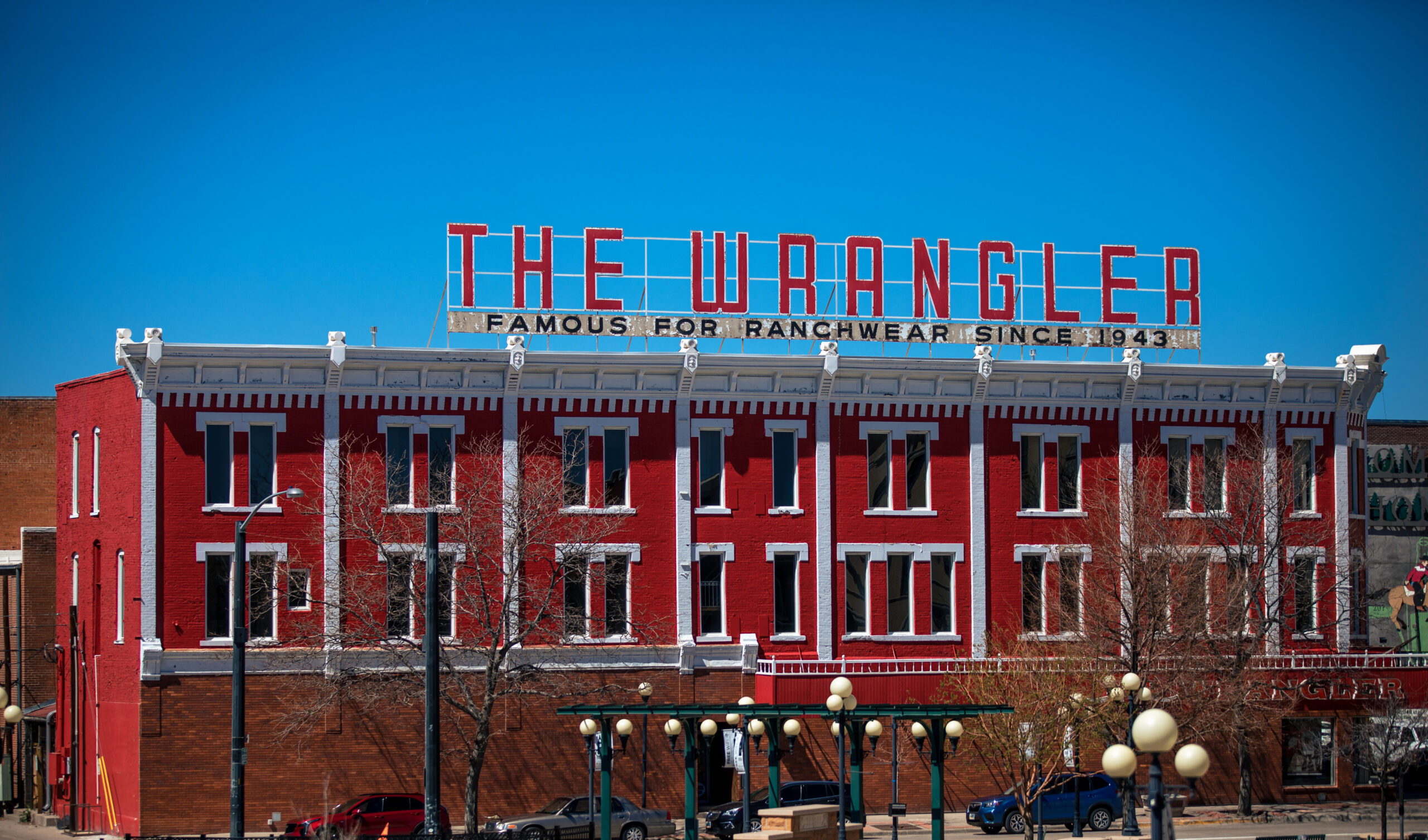 A side view of a large red-and-white building, topped with signage for The Wrangler.