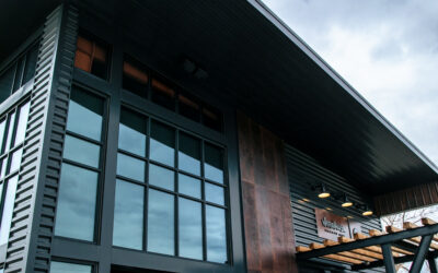Warehouse 21 – Vertical Vertical exterior of Warehouse 21, with open garage door and patio furniture outside.