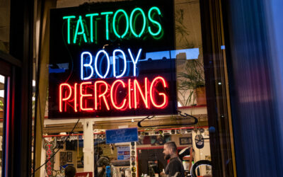 Neon Sign A neon sign for tattoos and body piercing glows from inside a tattoo parlor.