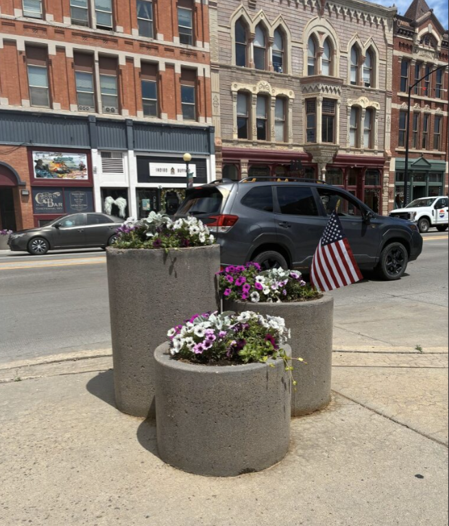 A trio of cement planters displays colorful white and purple flowers.