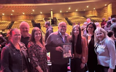 Fridays on the Plaza: GROUP-PHOTO A group of people smile as a plaque is presented.