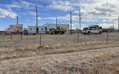THE CHILDRENS MUSEUM: BEFORE EMPTY LOT A chain link fence surrounds an open lot, inside of which work trucks and construction equipment are parked.