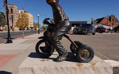 Bronze Statues A bronze statue of a young boy riding a tricycle.